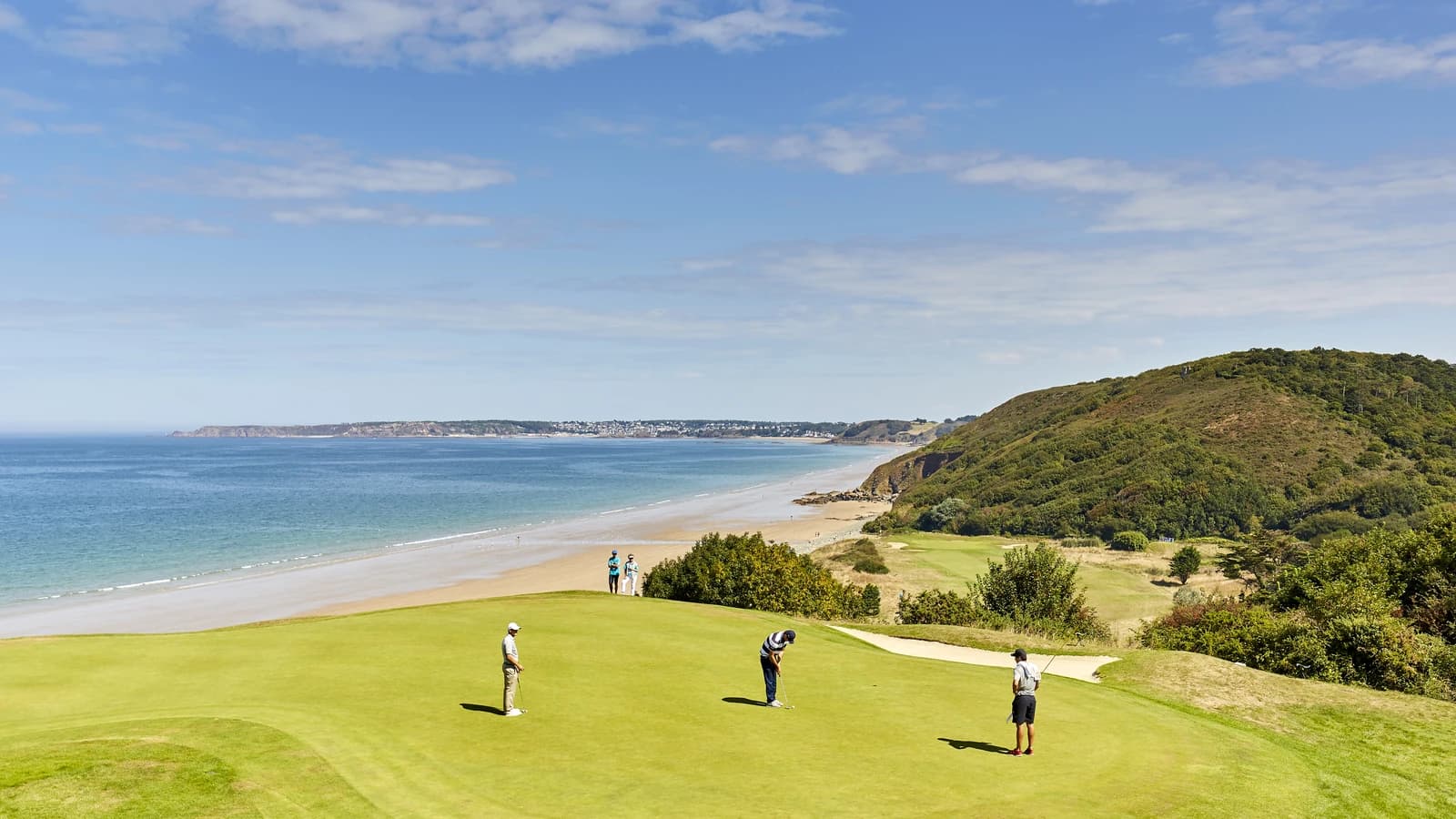 Golfeurs sur un green dominant la plage et les falaises au Golf Bluegreen Pléneuf-Val-André.