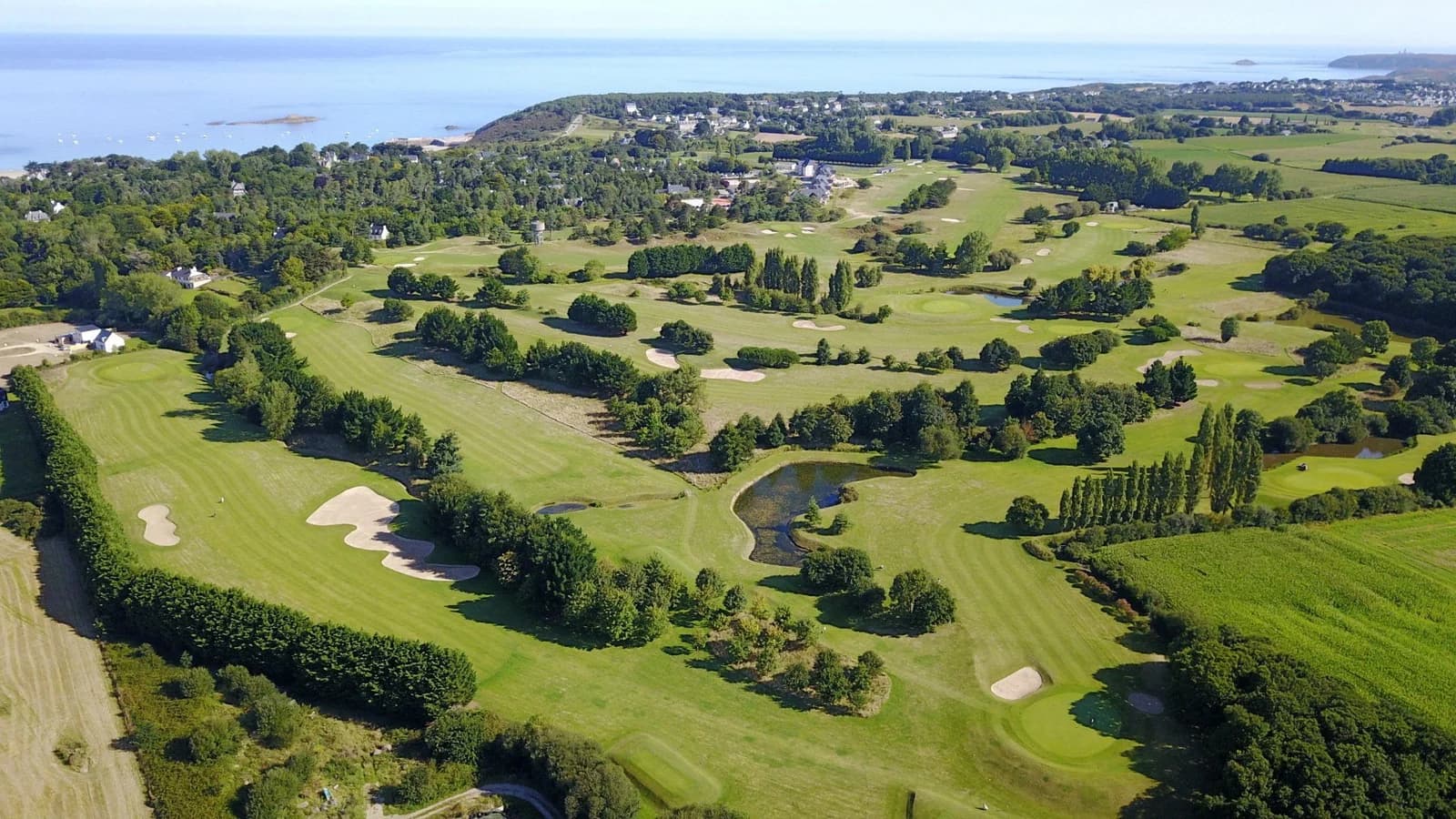 Vue aérienne du parcours du Golf de Fréhel Sables d’Or entre fairways, bunkers, pièces d’eau et littoral.