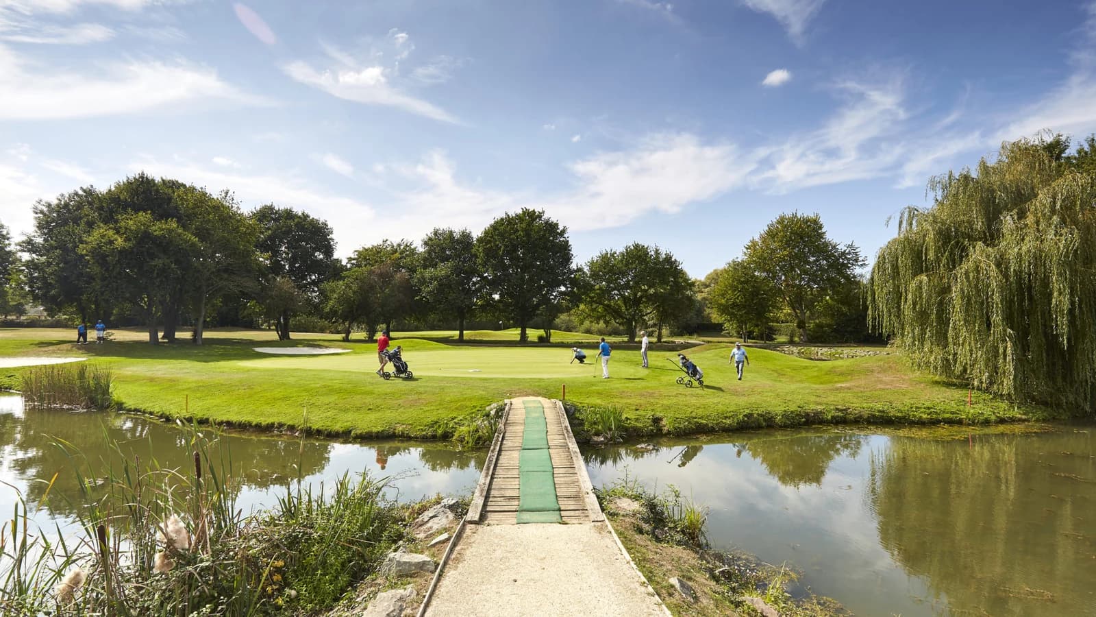Golfeurs sur un green bordé d’un plan d’eau au Golf Bluegreen Rennes Saint-Jacques.