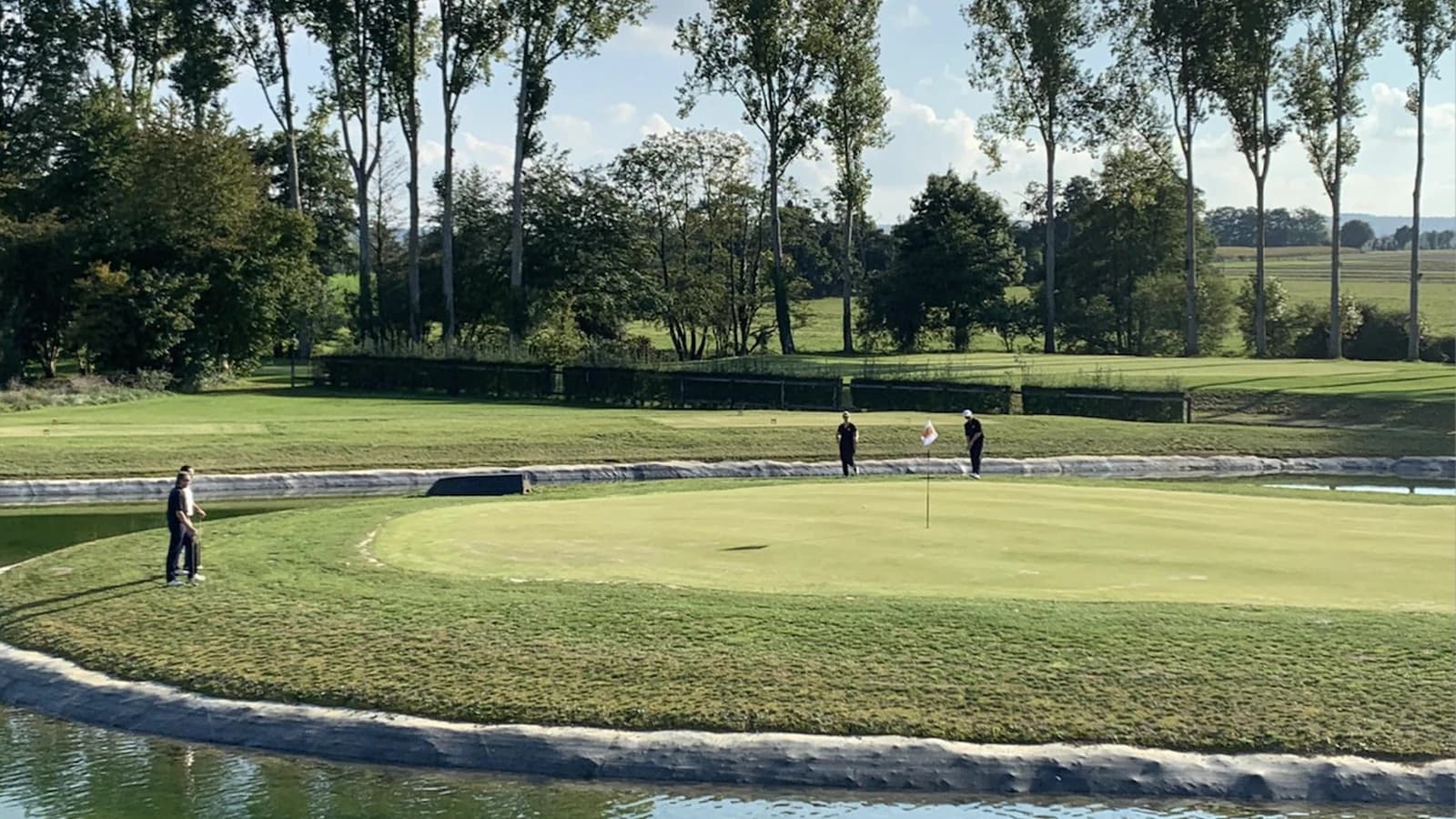 Green du Golf du Bief avec joueurs et obstacle d’eau.
