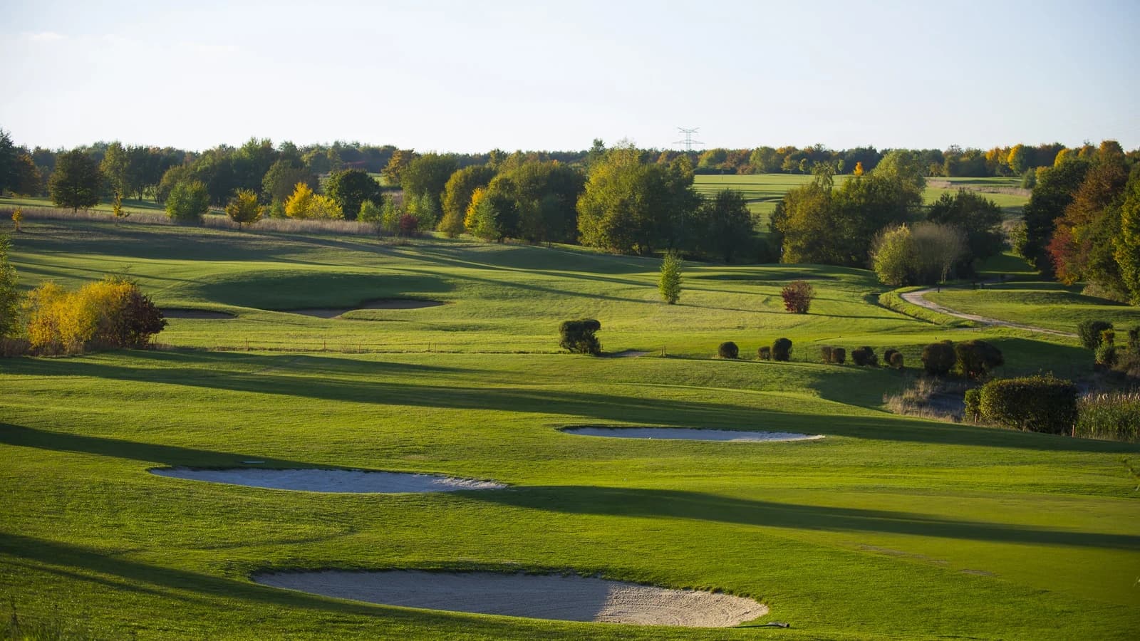 Fairways et obstacles d’eau du Golf municipal d’Évreux dans un paysage arboré.