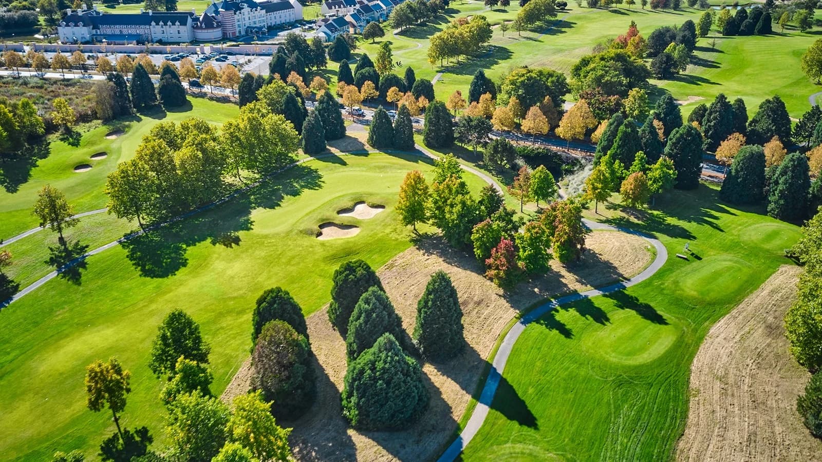 Vue aérienne d’UGOLF Paris Val d’Europe montrant les fairways, les bunkers et les arbres du parcours.