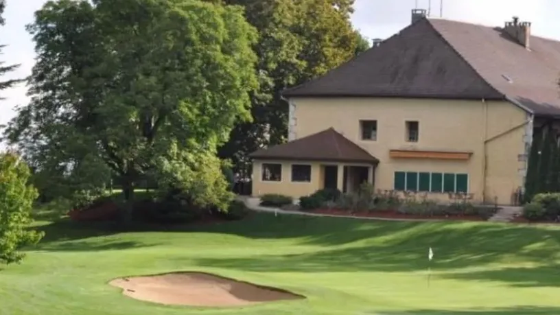 Green et bunker devant un bâtiment du domaine ; pas une photographie exclusivement hôtelière.