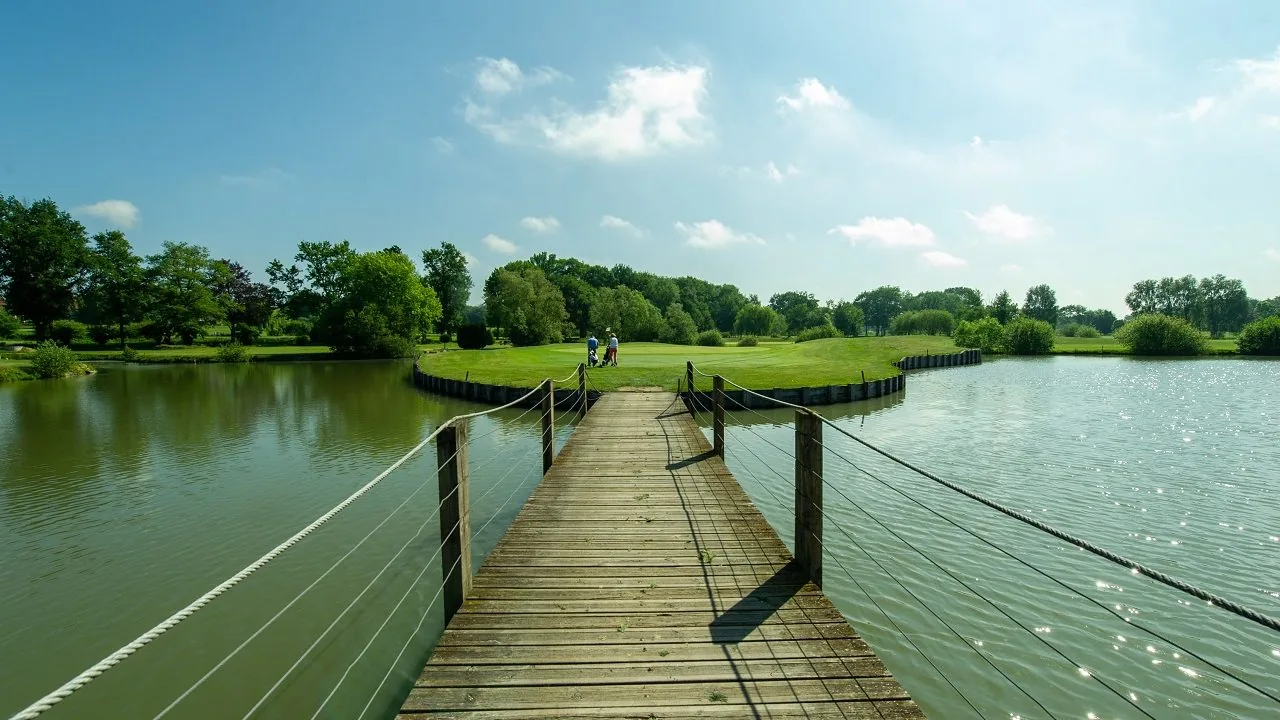 Passerelle vers un green entouré d’eau.