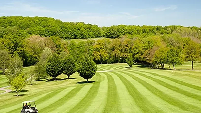 Fairway tondu en bandes, vallonnement et voiturette.