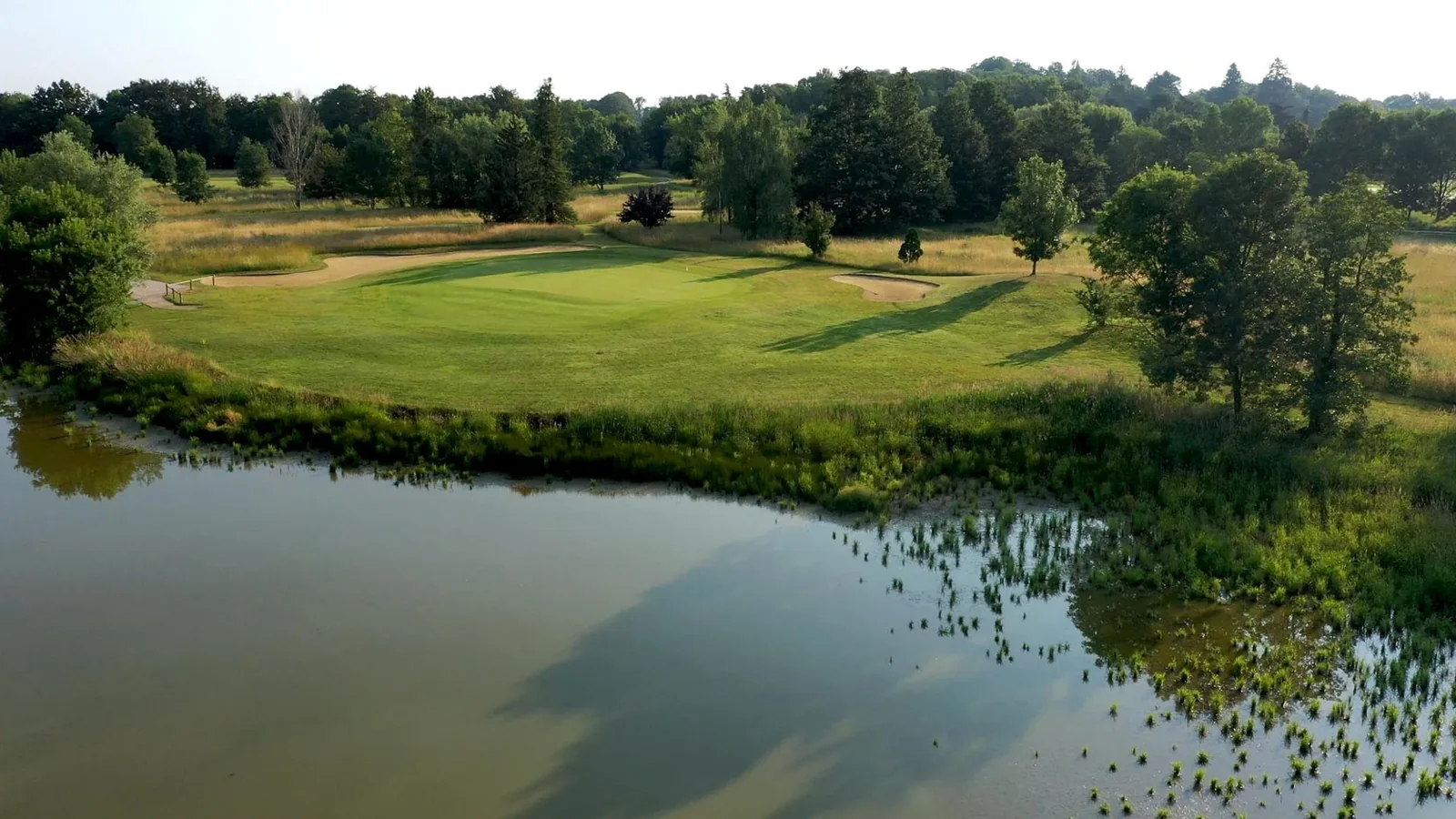 Green avec bunkers au-delà d’un plan d’eau, vue basse distincte.