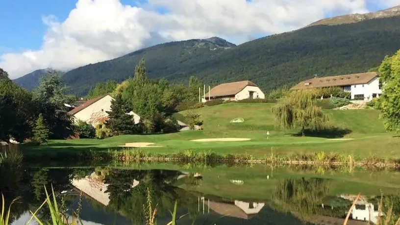 Green, plan d’eau et constructions au pied du relief.