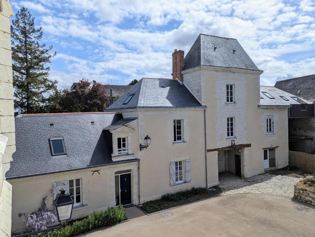 une vieille maison blanche avec un toit gris dans l'établissement Gîte du Château de saint Saturnin sur Loire, à Saint-Saturnin-sur-Loire