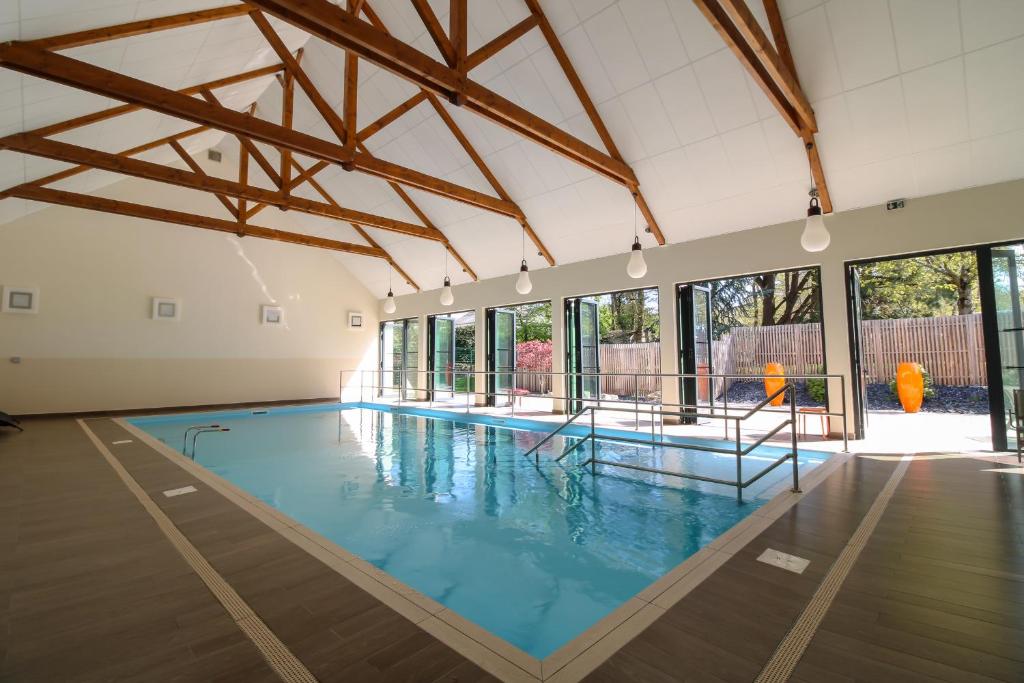 une grande piscine intérieure avec de l'eau bleue dans l'établissement Loire & Sens, à Juigné-sur-Loire