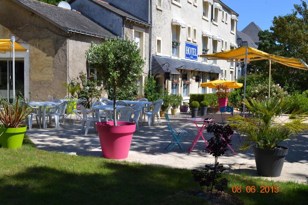 une terrasse avec des tables, des chaises et des plantes en pot dans l'établissement Hôtel Le Castel, à Brissac-Quincé