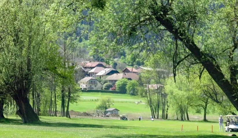 Allée de jeu arborée du Golf des Alpes et bâtiments en arrière-plan.