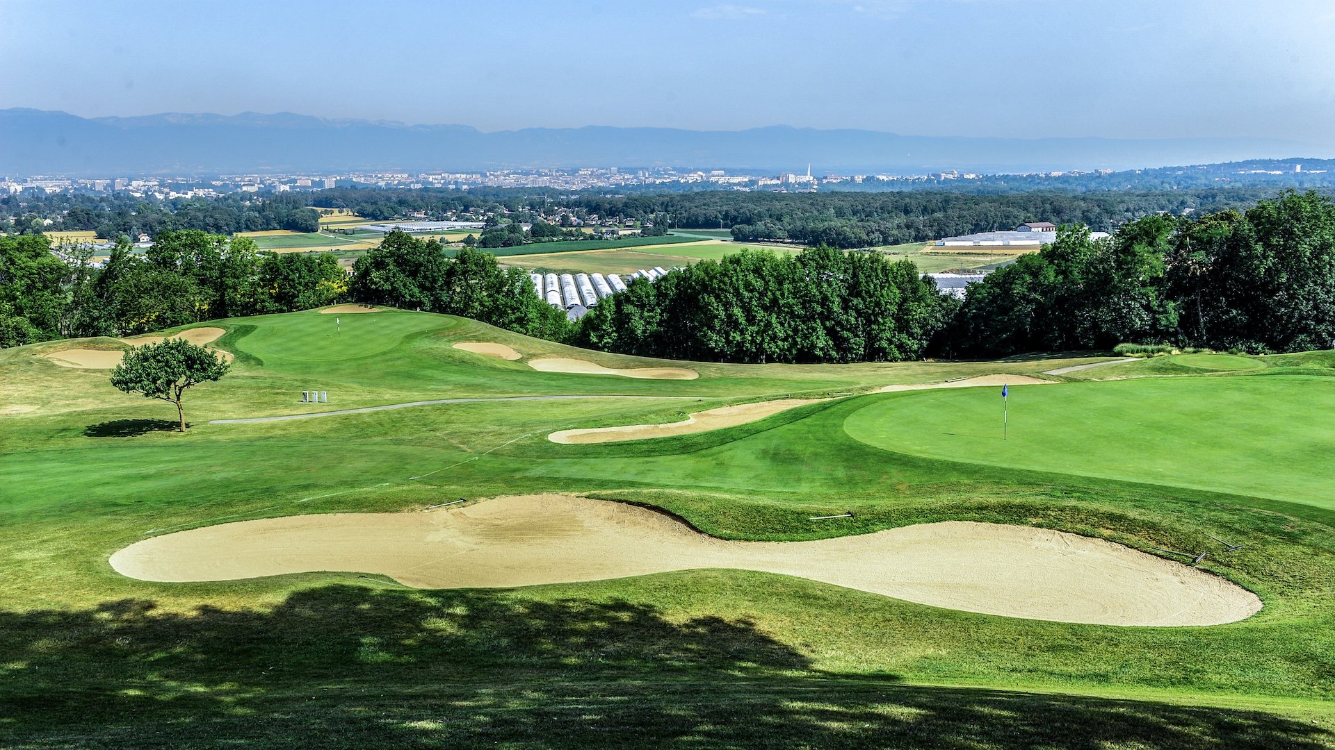 Green et bunkers du Golf & Country Club de Bossey, avec le paysage genevois à l’horizon.