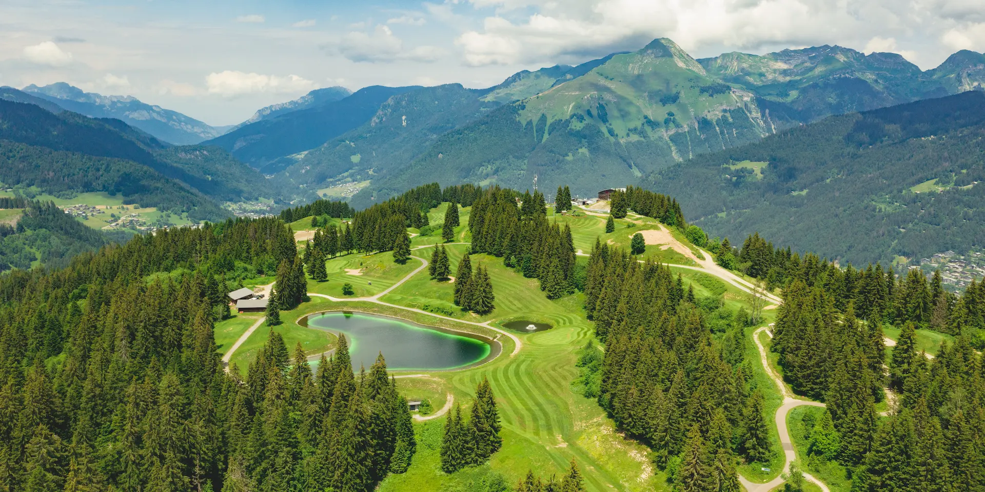 Panorama aérien du golf des Gets, de son plan d’eau et des montagnes environnantes.